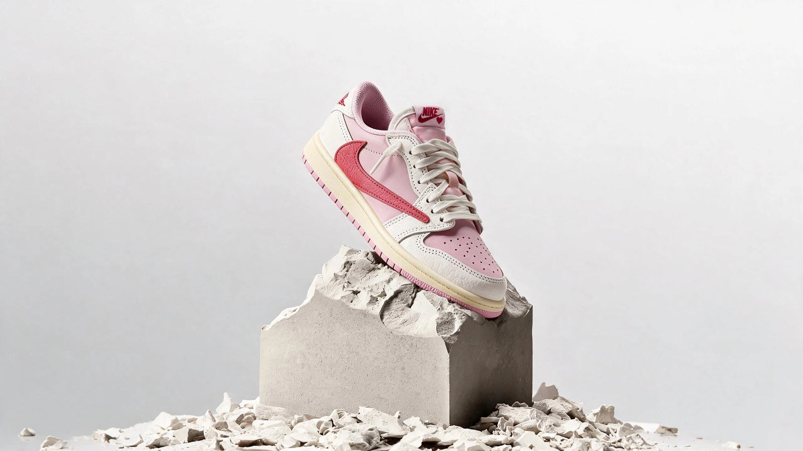 Air Jordan 1 Retro Low OG SP Travis Scott Sail Tropical Pink, sneakers rosa e rosse su un blocco di pietra